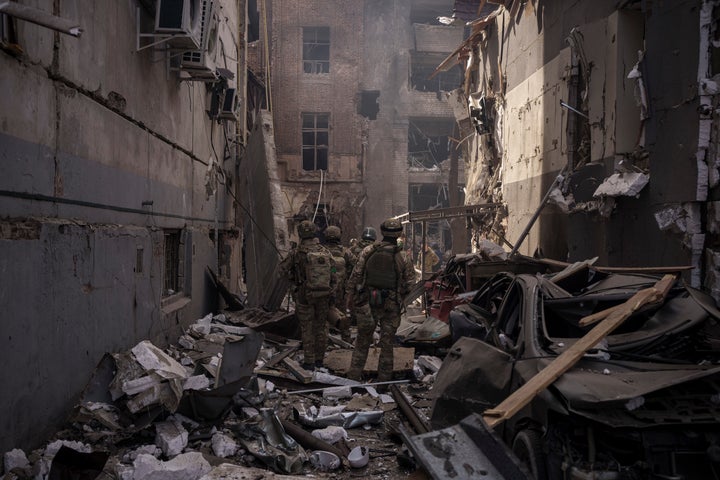 Ukrainian servicemen walk among debris of damaged buildings after a Russian attack in Kharkiv, Ukraine, Saturday, April 16, 2022.