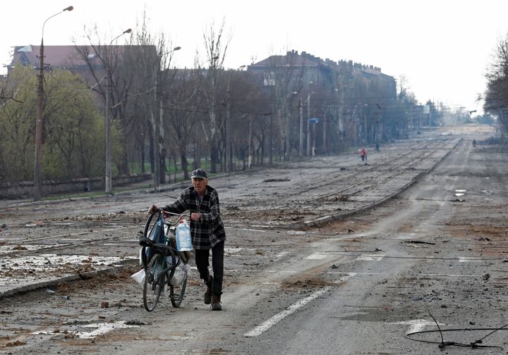 A local resident walks with a bicycle along a street near the Illich Steel and Iron Works during Ukraine-Russia conflict in the southern port city of Mariupol, Ukraine April 15, 2022.