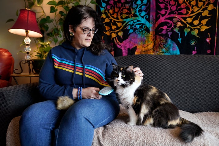 Tara Kramer sits in her apartment with her cat Busy, Friday, April 8, 2022, in Des Moines, Iowa. Month by month, more of the roughly 40 million Americans who get help buying food through the federal SNAP program are seeing their benefits plunge even as the nation struggles with the biggest increase in food costs in decades. (AP Photo/Charlie Neibergall)