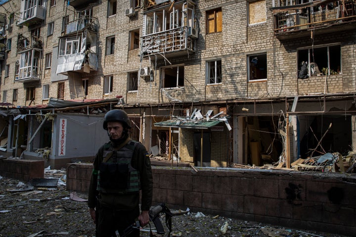 KHARKIV, UKRAINE - 2022/04/16: A Ukrainian soldier seen standing in front of a residential building destroyed by Russian artillery strike in Kharkiv. Russia has re-supplied its troops and concentrated the offensive on the eastern part of Ukraine, Kharkiv, the second biggest city in Ukraine now under constant threat of Russian bombardment and airstrikes. (Photo by Alex Chan Tsz Yuk/SOPA Images/LightRocket via Getty Images)