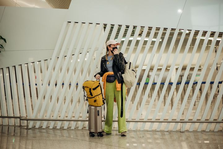 Young stylish woman with bag pack and luggage in the airport