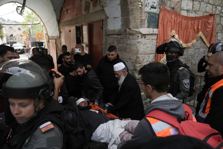 Paramedics carry a Palestinian injured by Israeli police in the Old City of Jerusalem, Sunday, April 17, 2022.