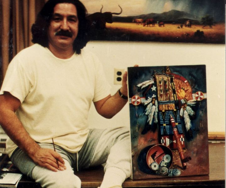 Leonard Peltier in prison in 1985, holding up one of his paintings. He has become an established artist while in prison.