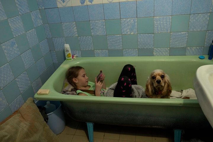 Zlata-Maria Shlapak sits inside a bathtub with her puppy Letti as an air siren goes off at an apartment her family took refuge in and currently renting on April 2. Zlata didn't see much fighting in Kharkiv, but "when she hears loud noises, she tries to hide," her mother said. (AP Photo/Nariman El-Mofty)