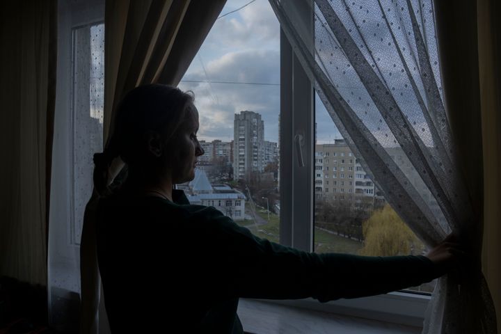 Olha Salivonchuk, head of the local association of apartment owners, looks out of the window in her living area on April 3. Olha has never considered leaving, even when a Russian airstrike in Lviv made their building shake. (AP Photo/Nariman El-Mofty)