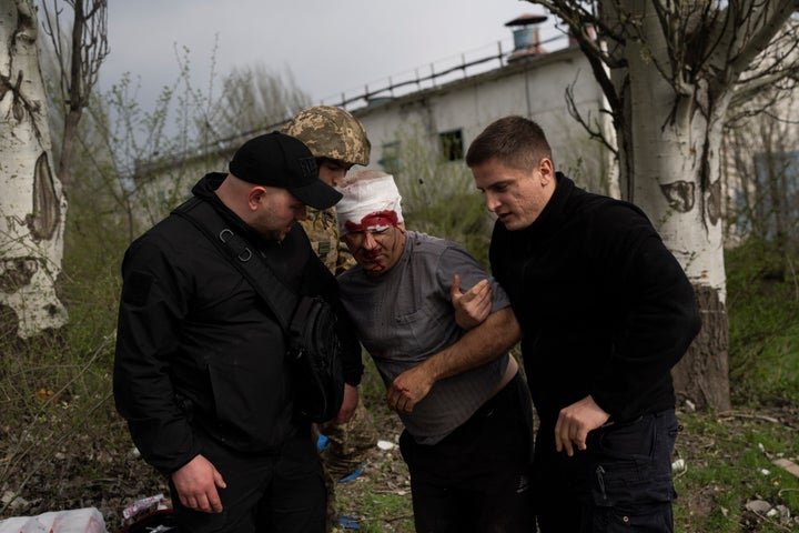 Des membres des forces de sécurité aident un homme blessé à la suite d'un bombardement russe d'une usine à Kramatorsk, dans l'est de l'Ukraine, le 19 avril 2022, tuant au moins une personne et en blessant trois autres. 