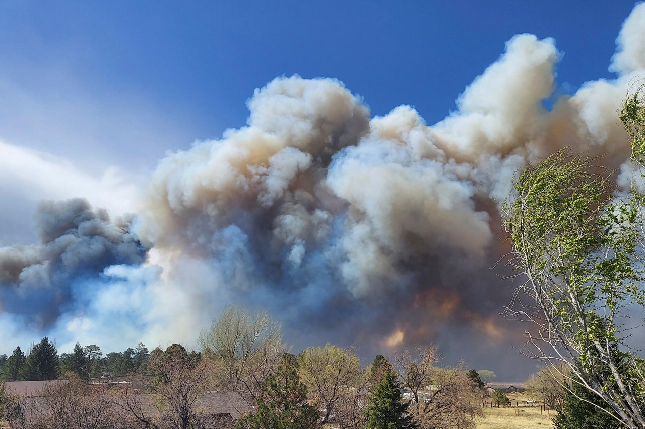 Smoke from a wind-whipped wildfire rises above neighborhoods on the outskirts of Flagstaff, Ariz., on April 19, 2022. Homes on the outskirts of Flagstaff were being evacuated Tuesday as high winds whipped a wildfire, shut down a major highway and grounded firefighting aircraft. 