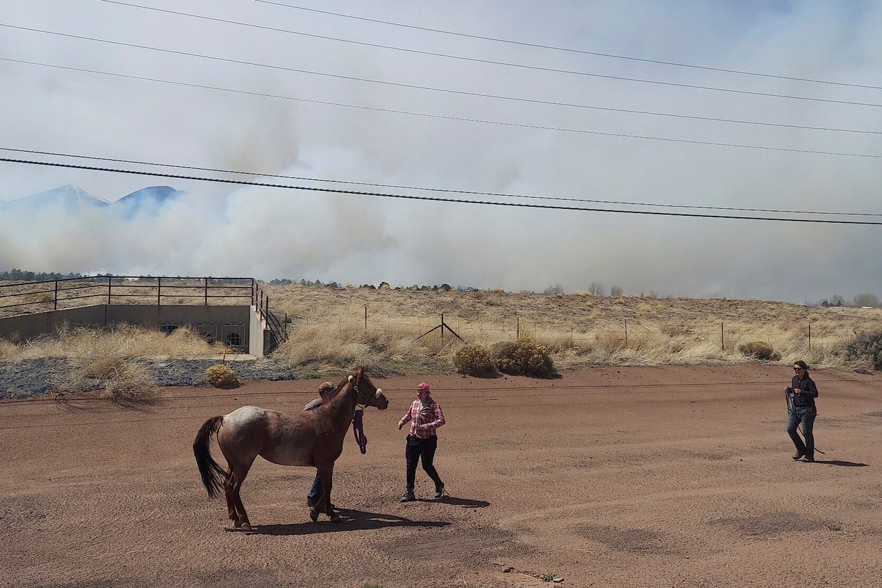 Smoke from a wind-whipped wildfire rises above neighborhoods on the outskirts of Flagstaff, Ariz., on TApril 19, 2022.