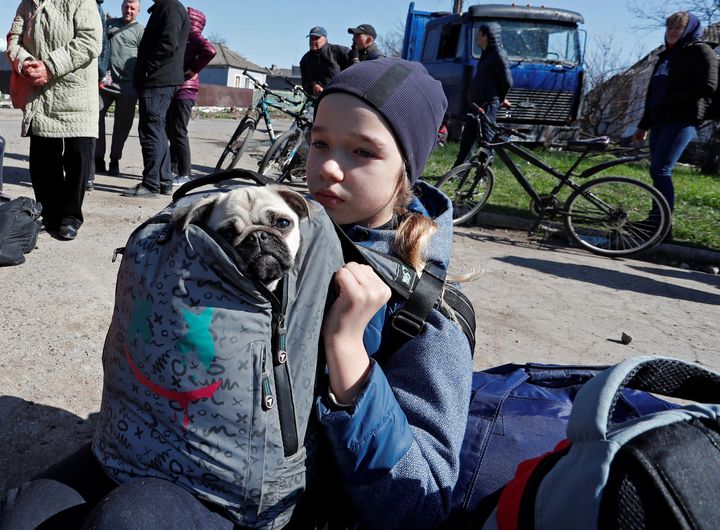 A child holds a dog as evacuees wait before boarding a bus to leave the city during Ukraine-Russia conflict in the southern port of Mariupol, Ukraine April 20, 2022. REUTERS/Alexander Ermochenko