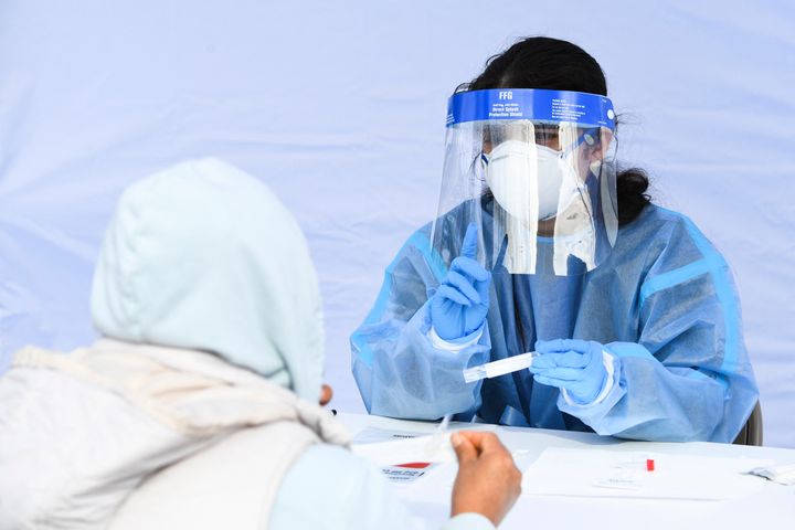 A healthcare worker gives instructions to a person on how to swab their nose as they receive testing for both rapid antigen and PCR Covid-19 tests at a Reliant Health Services testing site in Hawthorne, California on January 18, 2022. 