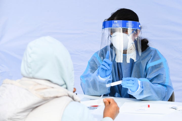 A healthcare worker gives instructions to a person on how to swab their nose as they receive testing for both rapid antigen and PCR Covid-19 tests at a Reliant Health Services testing site in Hawthorne, California on January 18, 2022.