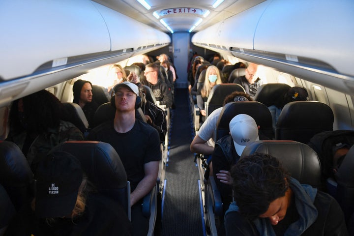 Airline passengers, some not wearing face masks, following the end of COVID-19 public transportation rules, sit during a American Airlines flight operated by SkyWest Airlines from Los Angeles International Airport in California to Denver, Colorado on April 19, 2022.