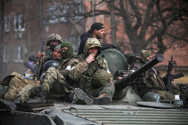 Service members of pro-Russian troops are seen atop of an armoured vehicle in the southern port city of Mariupol.