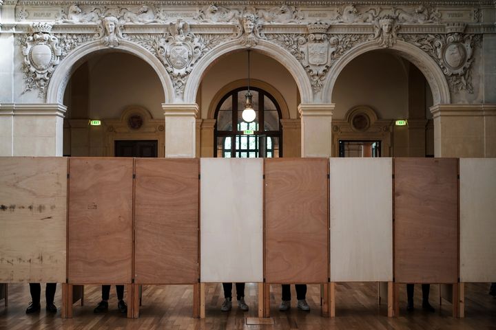 Voters stand in voting booths at a polling station in Lyon, central France, Sunday, April 24, 2022. (AP Photo/Laurent Cipriani)