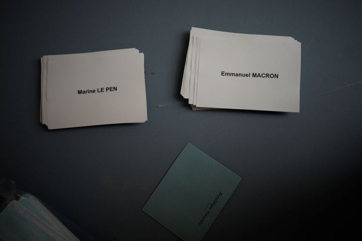 Papers showing the names of candidates are placed on a table as people prepare to vote during the second round of the French presidential election in Marseille, southern France, Sunday, April 24, 2022. (AP Photo/ Daniel Cole)