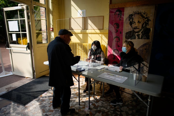 A man is about to cast his ballot in Sevres, near Paris, France, Sunday, April 24, 2022. (AP Photo/Christophe Ena)