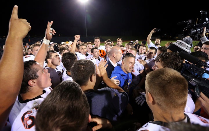 Kennedy (at center in blue) is surrounded by Centralia High School football players after they took a knee and prayed with him on the field following the team's game against Bremerton in 2015.