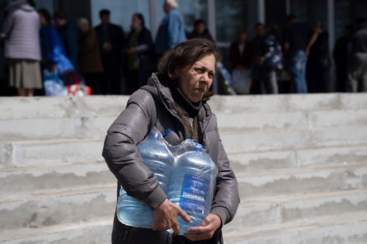 A woman carries bottles of drinking water from a distribution centre in Toretsk, eastern Ukraine on Monday, April 25, 2022. Residents have had no access to water for more than two months because of the war. 