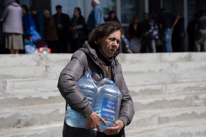 A woman carries bottles of drinking water from a distribution centre in Toretsk, eastern Ukraine on Monday, April 25, 2022. Residents have had no access to water for more than two months because of the war.