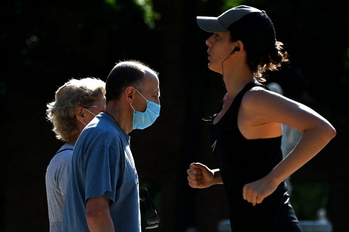Una deportista se cruza con una pareja, con mascarilla, en Madrid