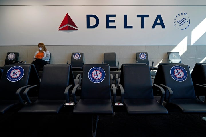 FILE - A passenger wears a face mask as she waits in a socially-distance area for a Delta Airlines flight, Wednesday, Feb. 3, 2021, at Hartsfield-Jackson International Airport in Atlanta. Delta Air Lines will start paying flight attendants during the time that passengers are boarding. That's a first for a major U.S. airline. Flight attendants in the U.S. generally don't begin getting paid until the doors close after boarding. Delta said Tuesday, April 26, 2022, that the change will take effect in June, and it comes on top of pay raises for flight attendants. The pay increase comes as Delta faces another attempt by unions to organize its non-union flight attendants. (AP Photo/Charlie Riedel, File)