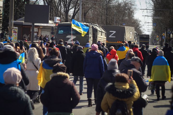 People with Ukrainian flags walk towards Russian army trucks during a rally against the Russian occupation in Kherson, Ukraine, on March 20, 2022. 