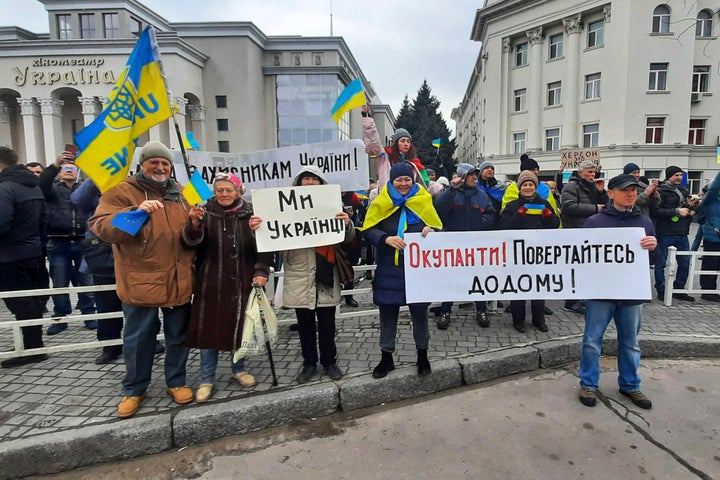 People hold Ukrainian flags and banners that read: "We are Ukrainians", centre, and "Occupiers! Return home!" during a rally against the Russian occupation in Svobody (Freedom) Square in Kherson, Ukraine, on March 5, 2022.