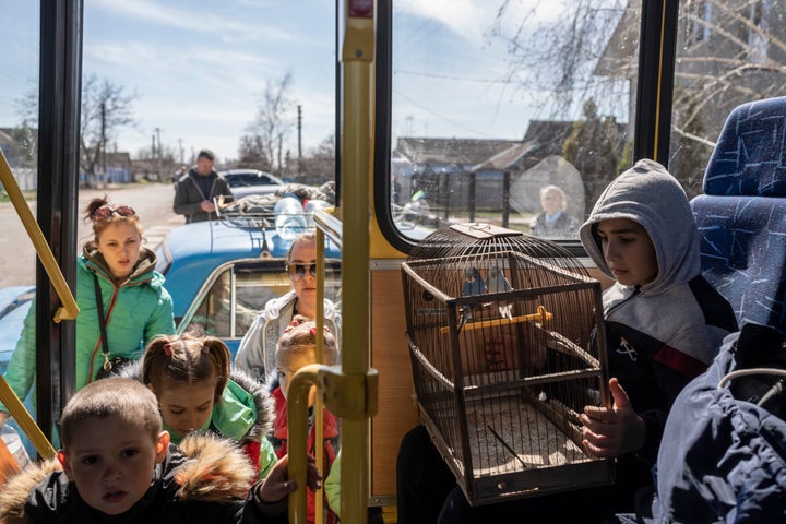 Ten-year-old Roma holds a cage with two parrots inside a bus leaving from the city of Bashtanka, Mikolaiv district, Ukraine, after he and his family flee from Kherson which is occupied by the Russian forces, on April 7, 2022.