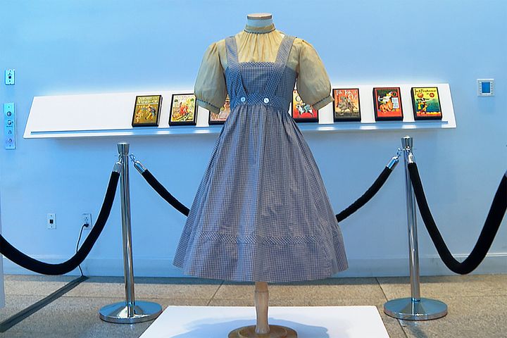 A blue and white checked gingham dress, worn by Judy Garland in the "Wizard of Oz," hangs on display, Monday, April 25, 2022, at Bonhams in New York. (AP Photo/Katie Vasquez)