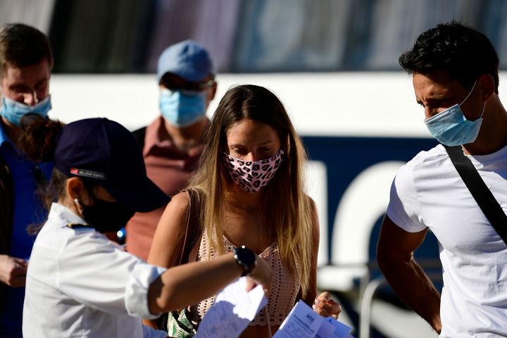 A ship company worker, wearing a face mask to protect against the spread of the new coronavirus, checks passengers' health questionnaires prior to their boarding, at the port of Piraeus, near Athens, Sunday, Aug. 30, 2020. Greek health officials said Friday that they are expanding for another two weeks a series of domestic health measures, including the obligatory use of masks in most indoors public areas, distancing on beaches and a ban on large gatherings on the occasion of religious festivals. (AP Photo/Michael Varaklas)