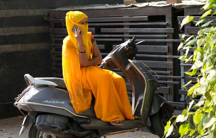 A woman sits with her face wrapped in a scarf on a hot summer day in Lucknow, in the central Indian state of Uttar Pradesh, Thursday, April 28, 2022.