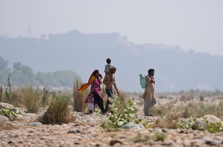 People walk towards the Tawi River to cool themselevs on a hot summer afternoon in Jammu, India, Thursday, April 28, 2022.