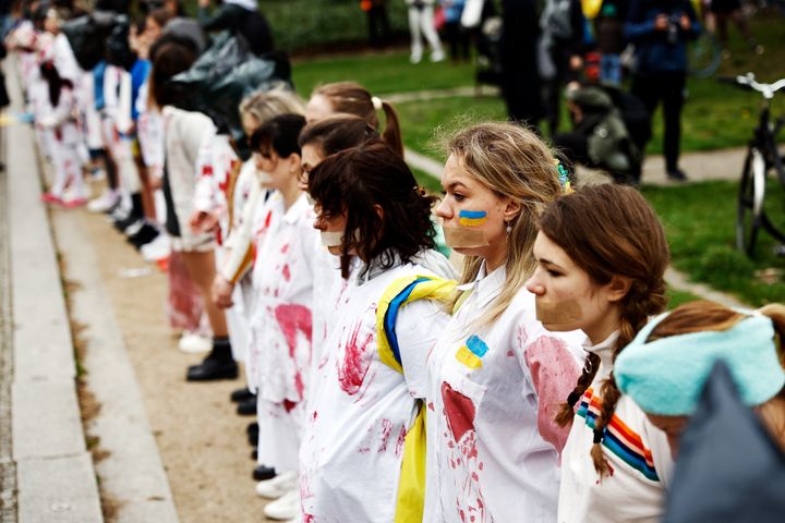 ドイツ・ベルリンで行われた、ロシアによるウクライナ侵攻における女性や少女への暴力に反対するデモ。人工血液のついた白い服を着て、手をつなぎながら抗議する女性たち（2022年4月21日撮影）
