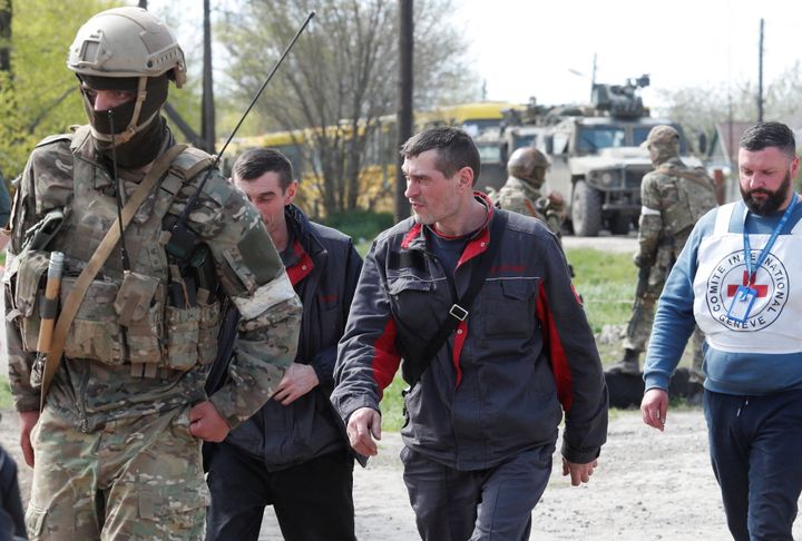 Civilians who left the area near Azovstal steel plant in Mariupol walk accompanied by a service member of pro-Russian troops and a member of the International Committee of the Red Cross (ICRC) at a temporary accommodation centre during Ukraine-Russia conflict in the village of Bezimenne in the Donetsk Region, Ukraine May 1, 2022. REUTERS/Alexander Ermochenko