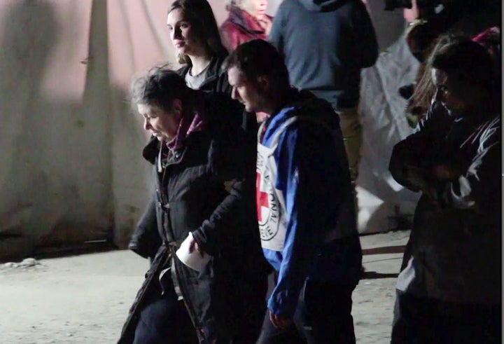 In this photo taken from video, civil evacuees accompanied by Red Cross personnel walk in an area controlled by Russian-backed separatist forces in Bezimenne, about 20 kilometres (12 miles) east of Mariupol, eastern Ukraine, Saturday, April 30, 2022. Ukrainian President Volodymyr Zelenskyy has confirmed that an evacuation is underway of civilians at a steel plant in the bombed-out city of Mariupol. Zelenskyy said on social media Sunday that a group of 100 people are on their way from Azovstal steelworks to Ukrainian-controlled territory.