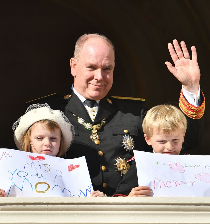 Prince Albert II of Monaco with his children showing "We miss you mom" and "We Love you mommy" drawings.