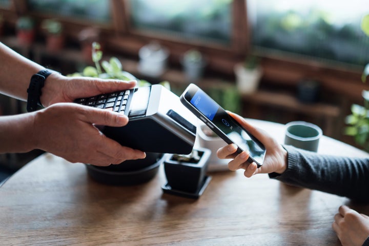 Persona pagando con su teléfono móvil.