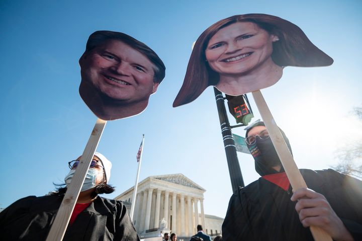 Reproductive rights activists hold images of Supreme Court Justices Brett Kavanaugh and Amy Coney Barrett during oral arguments in Dobbs v. Jackson Women's Health Organization.