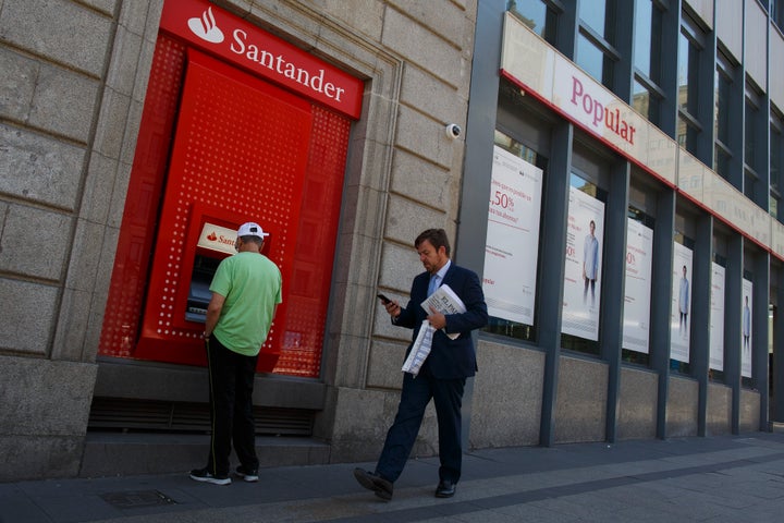 Un hombre camina ante un cajero del Banco Santander y una de las antiguas entidades del Popular, en una foto de archivo.