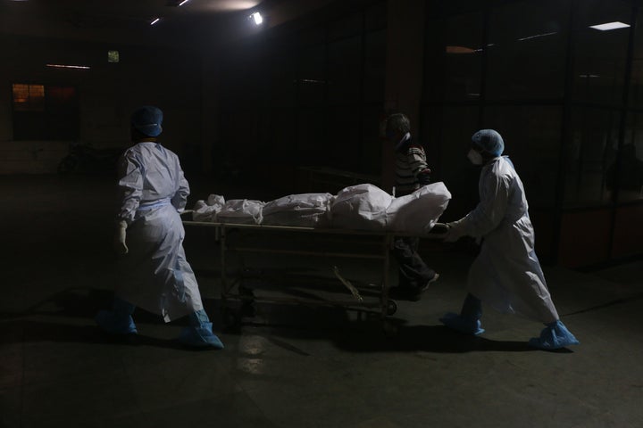 Foto de archivo de trabajadores sanitarios llevando a una persona muerta por Covid en India.