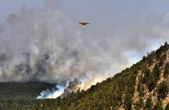 A firefighting plane flies over a plume of smoke near Las Vegas, New Mexico on Wednesday, May 4, 2022.