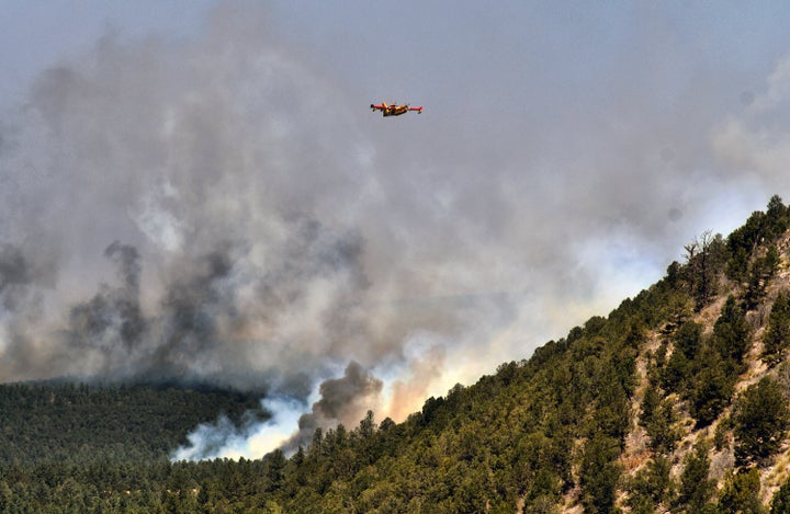 A firefighting plane flies over a plume of smoke near Las Vegas, New Mexico on Wednesday, May 4, 2022. 