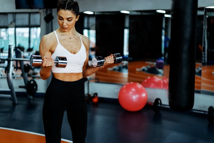 Training young sports woman in the gym with small weights