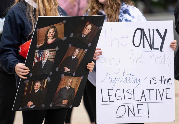 A pro-choice demonstrator holds a placard showing the 6 conservative Supreme Court Justices outside the Supreme Court in Washington, D.C., on May 5, 2022.