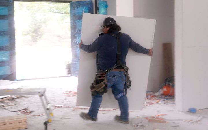 Samuel, originally from Mexico and who only wished to share his first name, moves sheetrock as he works at a home under construction in Plano, Texas, on May 3.