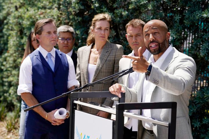 Charles Johnson, right, is surrounded by his legal team Chris Dolan, left, in blue, Courtney Rowley, center, and Nick Rowley, second from right, during a press conference announcing a lawsuit outside Cedars-Sinai Medical Center.