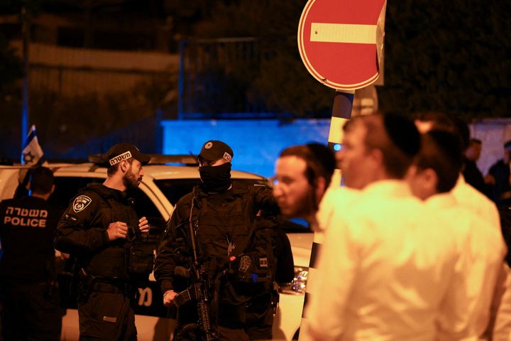 Κάτοικοι της περιοχής και αστυνομικοί είναι συγκεντρωμένοι έξω από το σημείο της επίθεσης κατά την οποία σκοτώθηκαν τρεις Ισραηλινοί.