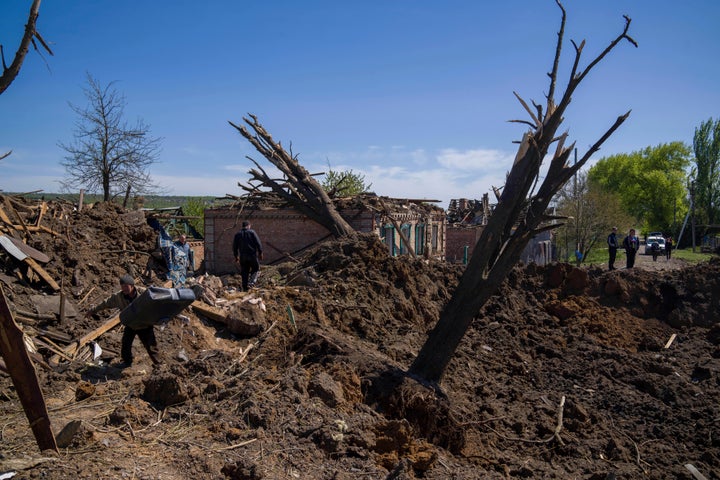 La gente limpia los escombros en una zona residencial después del ataque aéreo ruso en Bakhmut, región de Donetsk, Ucrania, el sábado 7 de mayo de 2022. (Foto AP/Evgeniy Maloletka)
