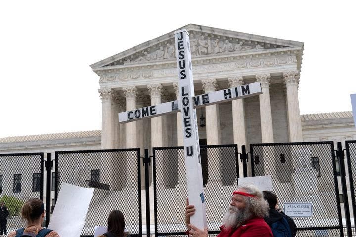 A demonstrator holding a cross protests outside of the U.S. Supreme Court, Thursday, May 5, 2022, in Washington. America’s faithful are bracing, some with cautionary joy and others with looming dread, for the Supreme Court to potentially overturn the landmark 1973 Roe v. Wade decision and end the nationwide right to legal abortion.