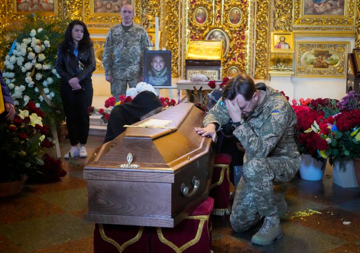 A soldier pays his last tribute to volunteer soldier Oleksandr Makhov, 36, a well-known Ukrainian journalist, killed by Russian troops, during his funeral at St Michael cathedral in Kyiv, Ukraine, Monday, May 9, 2022. (AP Photo/Efrem Lukatsky)